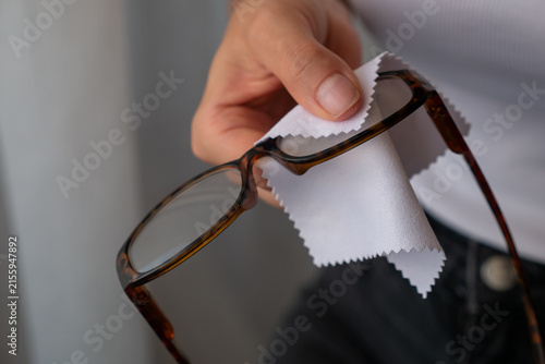 Woman cleaning eyeglasses lens with microfiber cloth for clear vision and eyewear care.