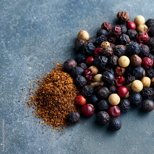 An assortment of vibrant peppercorns and spices on a textured surface.