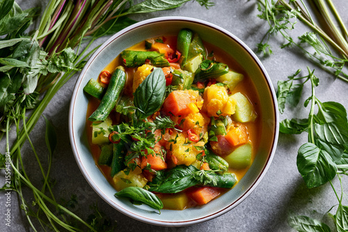 A vibrant bowl of vegetable stew garnished with fresh herbs and spices.