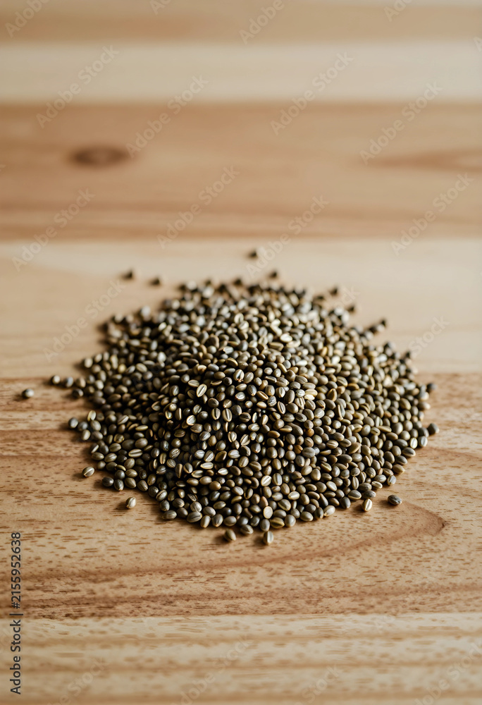 Fototapeta premium Pile of organic hemp seeds on a light wooden surface, healthy eating and superfood for nutrition and wellness, the natural plant based ingredient is suitable for various diets and culinary uses