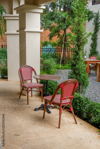 Luxury chair and wooden table set in english garden on a sunny day,outdoor seating for restaurant or cafe,Near paver patio with sitting area and small garden in forest.