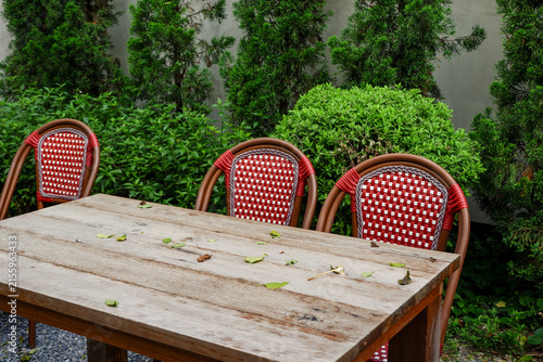 Luxury chair and wooden table set in english garden on a sunny day,outdoor seating for restaurant or cafe,Near paver patio with sitting area and small garden in forest.