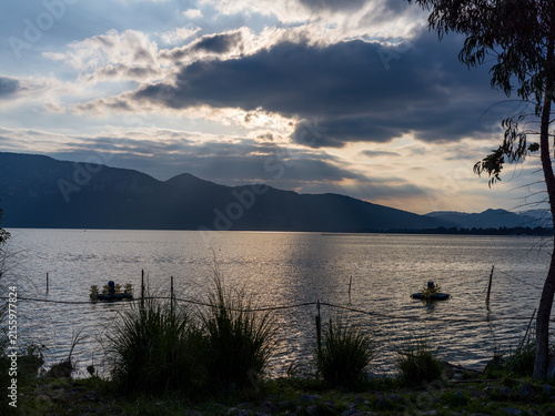 Foto Wide lake under dramatic cloudy sky with sunbeams reflecting on water