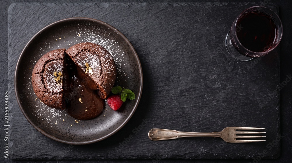 Fototapeta premium Chocolate lava cake with flowing liquid center and red wine on slate board