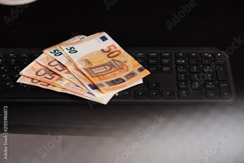 Euro banknotes resting on computer keyboard