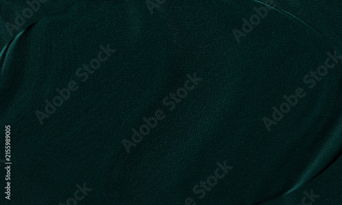 Dark green velvet fabric texture background with soft shadows and elegant folds.