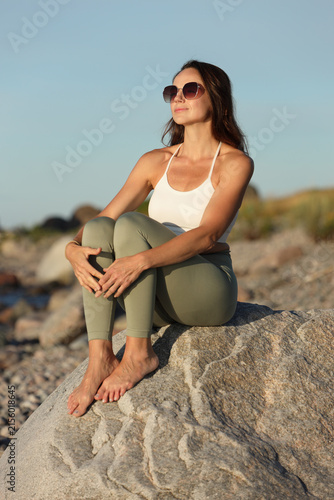 Woman Relaxing on Rocky Beach Enjoying Summer Sunshine
