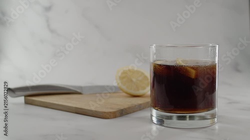 Adding more soda in glass. Cutting board with knife and lemon on back. Original sound. 24fps. Prores 422HQ