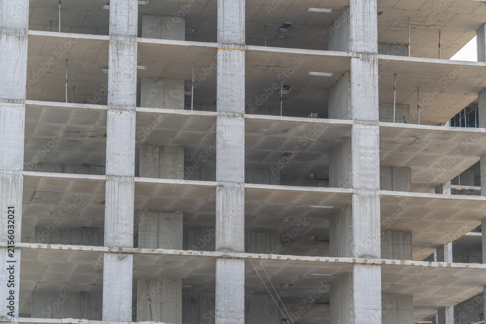 Fototapeta premium New building structure is under construction in a busy city, showing raw concrete and empty floors in the early afternoon