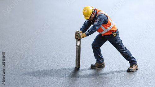 Construction Worker in Safety Gear Pushing Steel Post on Industrial Floor