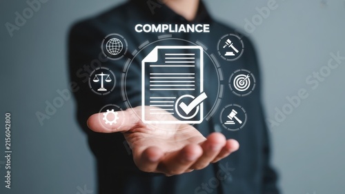 Businessman holding virtual compliance document icon with legal symbols.