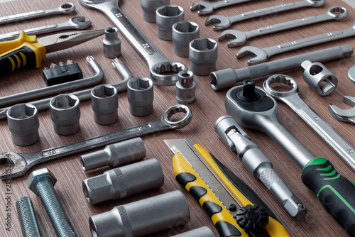 A combination tool set for auto repair shops, repairs, and installations. Wrenches, socket wrenches, torque wrench, and sockets are arranged on a work bench. Top view.