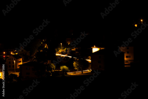 Konstfotografi Village de Travers dans le Val-de-Travers en Suisse illuminé la nuit, avec les maisons éclairées au cœur du paysage sombre du Jura