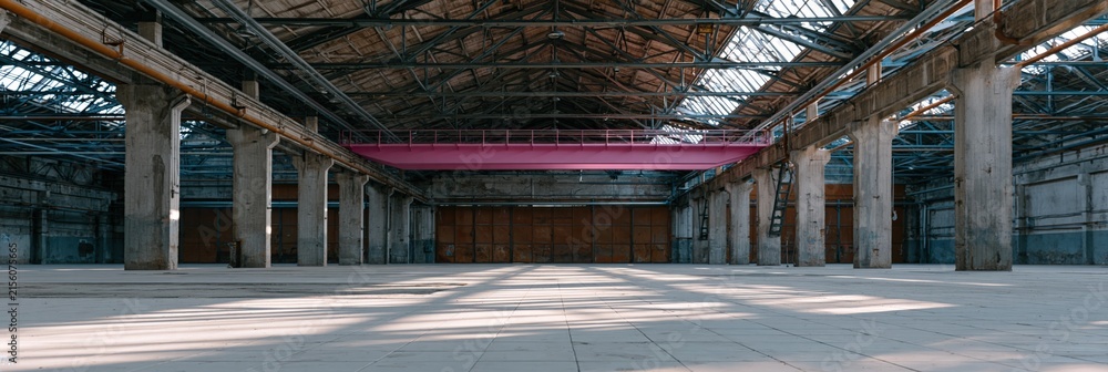 Fototapeta premium Raw empty industrial warehouse interior with weathered beams and skylight shadows for background banner and vintage style wallpaper