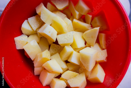 Canvas Print Freshly cut peeled potato pieces collected in a bright red bowl, showing clean chunks prepared for cooking and a simple homemade food ingredient