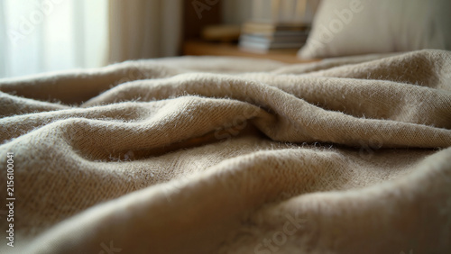 Luxury beige cashmere fabric texture close up with soft flowing wool folds in warm light