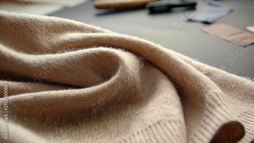 Luxury beige cashmere fabric texture close up with soft flowing wool folds in warm light