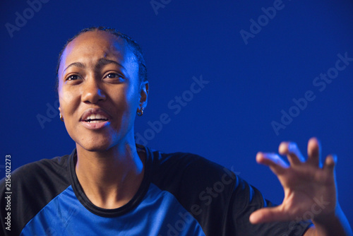 Canvas Print African American woman speaking and reaching in studio with blue athletic shirt