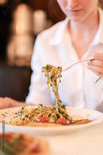 Frau sitzt als Gast im Restaurant und isst eine Speise Pasta