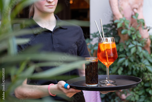 Bedienung trägt bei der Arbeit im Restaurant ein Tablett mit Getränken