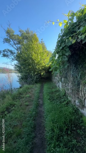 Narrow dirt path beside a river and an old stone wall