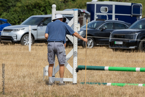 Photography Show jumping course builder measuring the height of a fence at a horse show