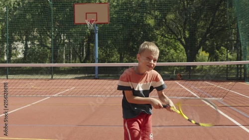 Young boy rehearsing tennis shots during court warm-up