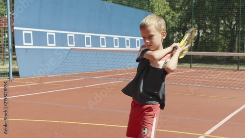 Young boy rehearsing tennis shots during court warm-up