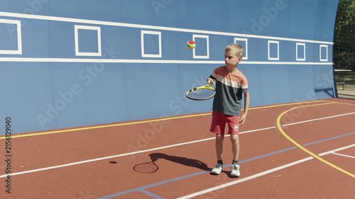 Young boy practicing tennis skills by bouncing a ball on his racket