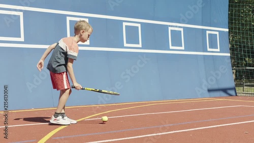 Young boy practicing tennis skills by bouncing a ball on his racket