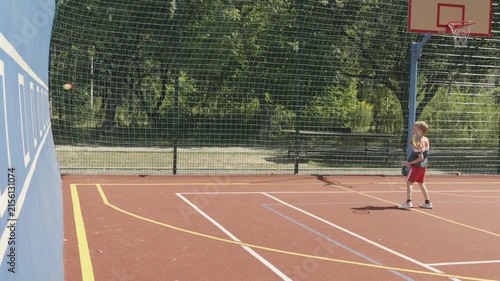 Slow motion. 7-year-old boy training his tennis skills against a practice wall