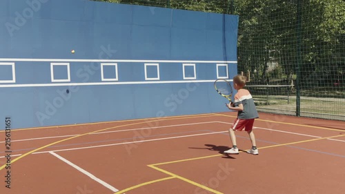 Slow motion. 7-year-old boy training his tennis skills against a practice wall