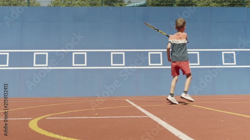 Slow motion. 7-year-old boy training his tennis skills against a practice wall
