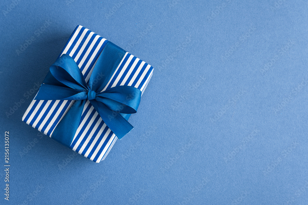 Obraz premium Gift box with blue ribbon on blue background celebration surprise present giving joy special occasion