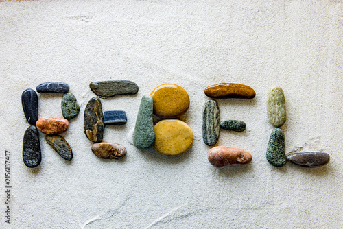 Fotografie REBEL word formed with natural stones on beach sand