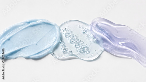 Luxury skincare cosmetic textures in translucent icy-blue and pale-lavender gels with glossy surfaces and delicate air bubbles on a clean white background.