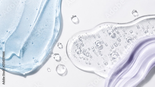 Luxury skincare cosmetic textures in translucent icy-blue and pale-lavender gels with glossy surfaces and delicate air bubbles on a clean white background.
