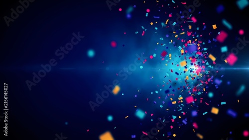 Colorful paper confetti pieces scatter through the air during an energetic party explosion set against a dark blue background featuring bright glowing lights and celebratory atmosphere