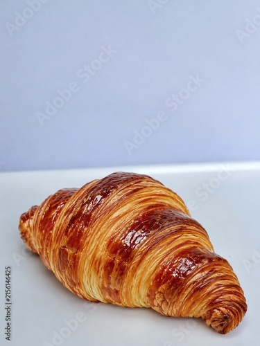 Canvastavla Freshly baked golden French croissant on light blue background