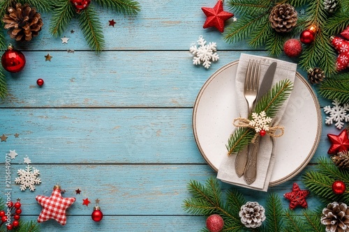festive Christmas table setting with fir branches and holiday decorations on weathered pastel blue wooden  background