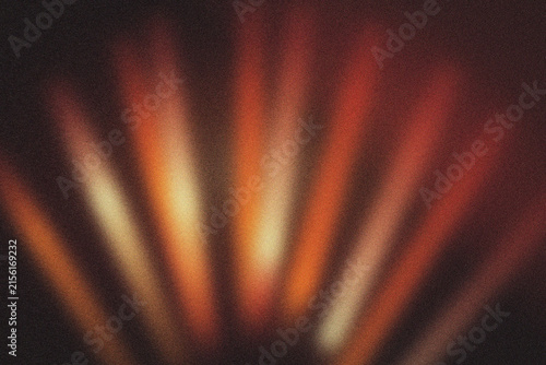 Soft focus abstract background of radiating orange and yellow light beams with a grainy texture effect