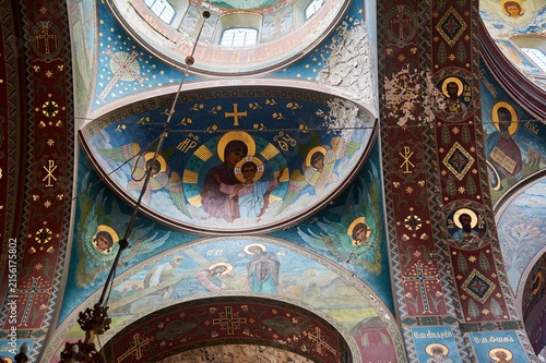 Dome and vault frescoes in an Orthodox church. Virgin Mary with Child, angels, scene of carrying the cross. Peeling plaster, ancient murals, rich religious symbolism.