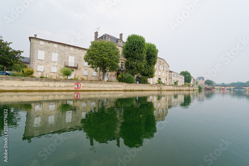 Obraz na plátne La Charente à Jarnac offre un décor paisible où le fleuve méandre doucement, bordé de quais historiques, de chais réputés et de parcs verdoyants invitant à la flânerie et aux loisirs nautiques