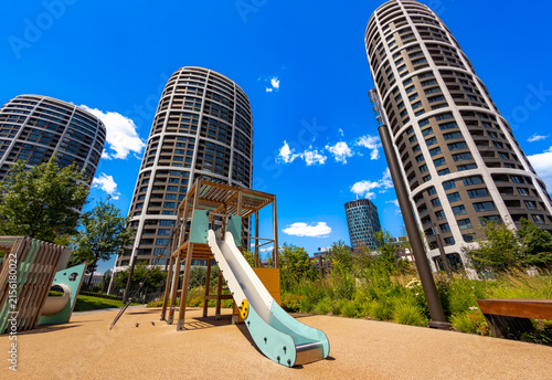 Photography Playground area with wooden slide in front of modern skyscrapers