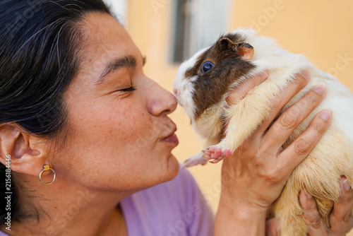 Woman kissing guinea pig showing pet affection