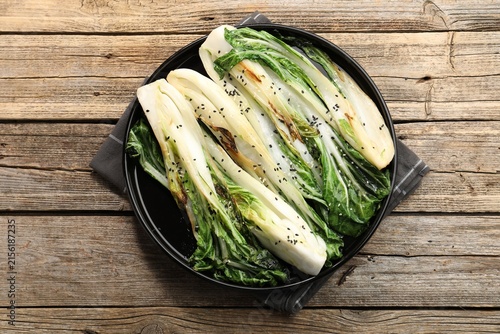 Foto Tasty cooked bok choy cabbages with sesame seeds and sauce served on wooden tabl