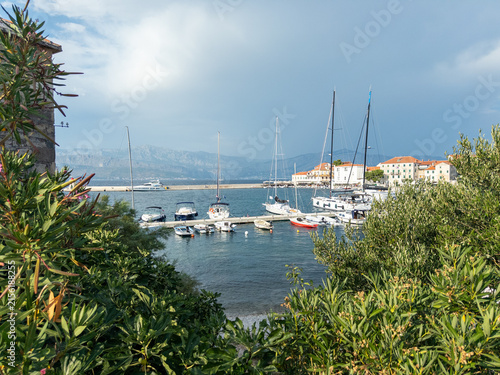 Scenic view of marina with sailboats and coastal buildings under cloudy sky in Mediterranean region
