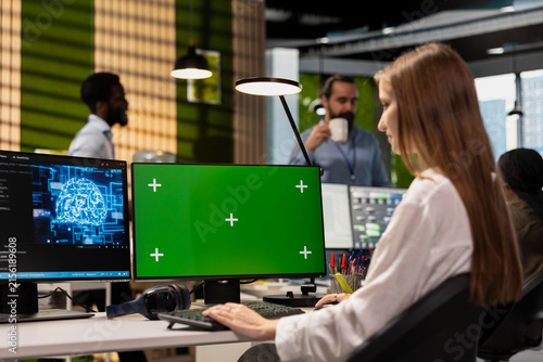 фотографія Junior developer at a technology startup uses AI on a green-screen computer to optimize performance, forecast issues and train machine learning models while writing code in an office
