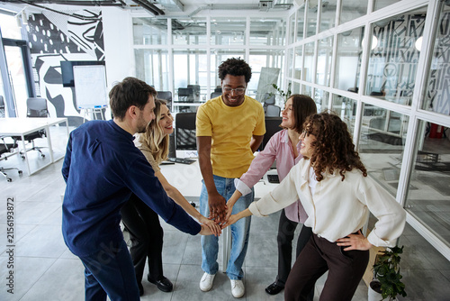 Fotografía Diverse business team joining hands during a collaborative office meeting