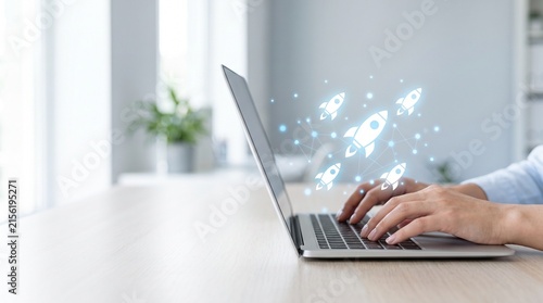 Business startup growth concept with rocket icons flying out of laptop while hands type on keyboard in bright office for success, innovation, and digital marketing strategy development.